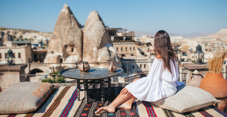 Happy young woman during sunrise watching hot air balloons in Cappadocia, Turkey
